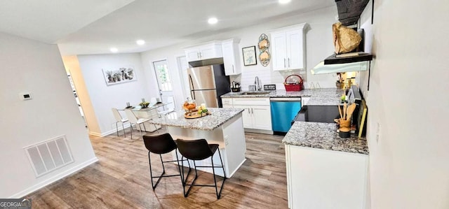 kitchen with white cabinets, a sink, visible vents, freestanding refrigerator, and dishwashing machine