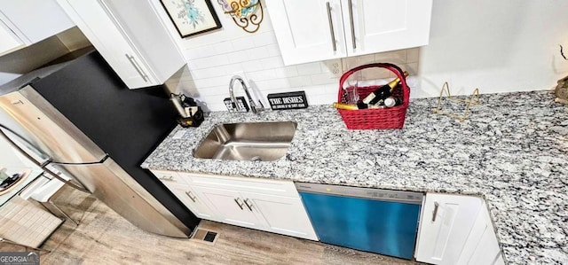 kitchen featuring dishwasher, light stone countertops, white cabinetry, a sink, and backsplash