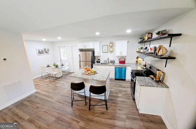 kitchen with white cabinets, appliances with stainless steel finishes, light wood-style floors, and visible vents