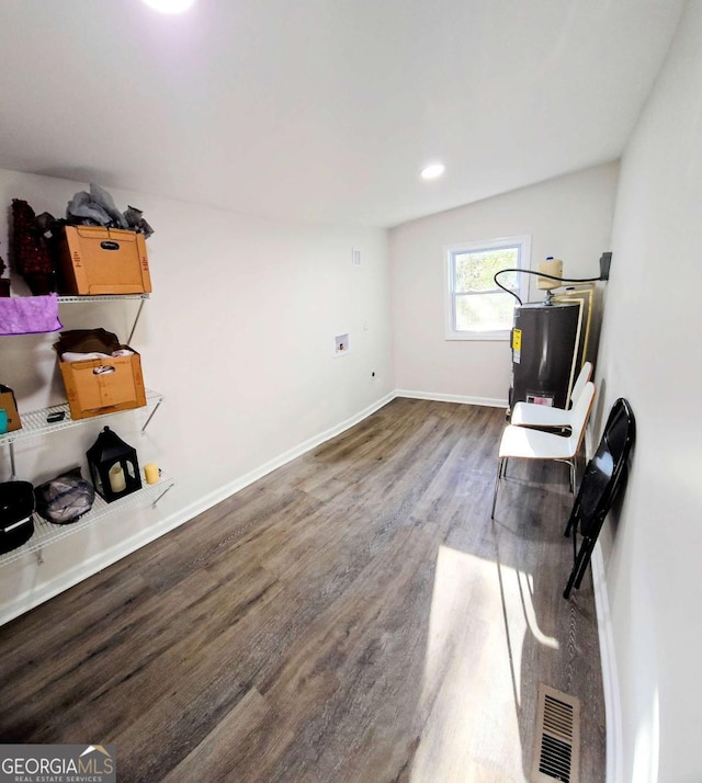 interior space with water heater, baseboards, visible vents, and wood finished floors
