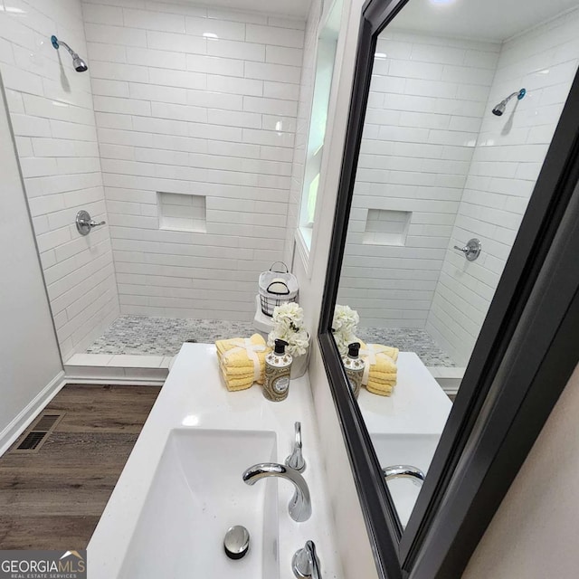 full bathroom featuring a stall shower, visible vents, wood finished floors, and a sink