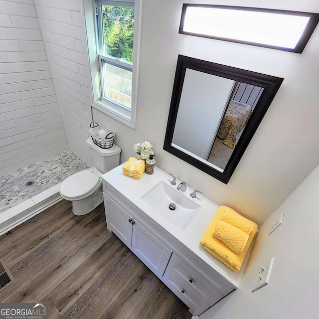 bathroom with a stall shower, toilet, wood finished floors, and vanity