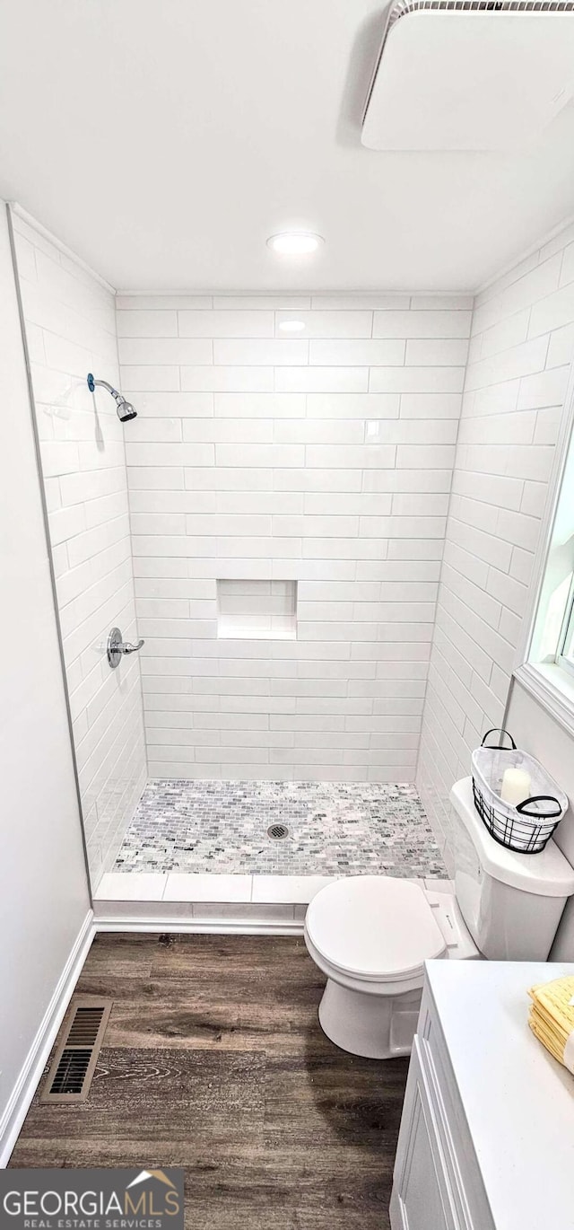 full bath featuring a stall shower, visible vents, wood finished floors, and toilet