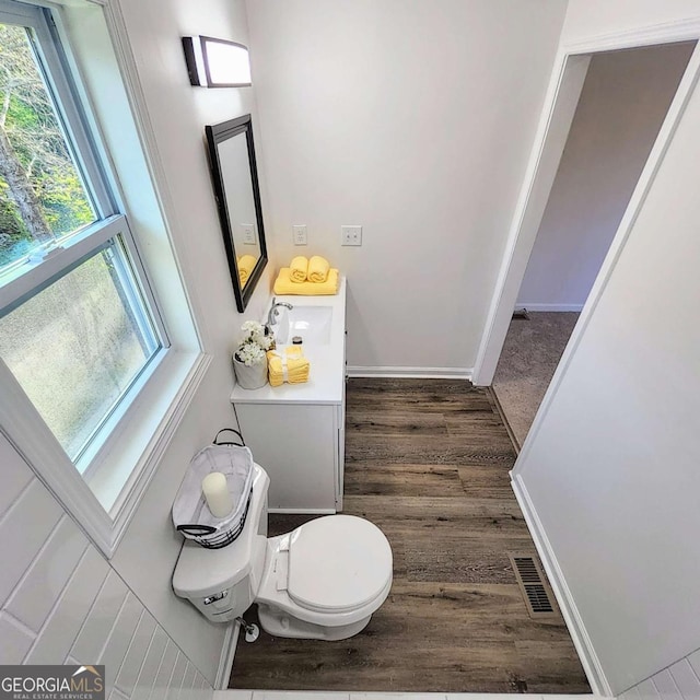 bathroom featuring toilet, baseboards, a sink, visible vents, and wood finished floors