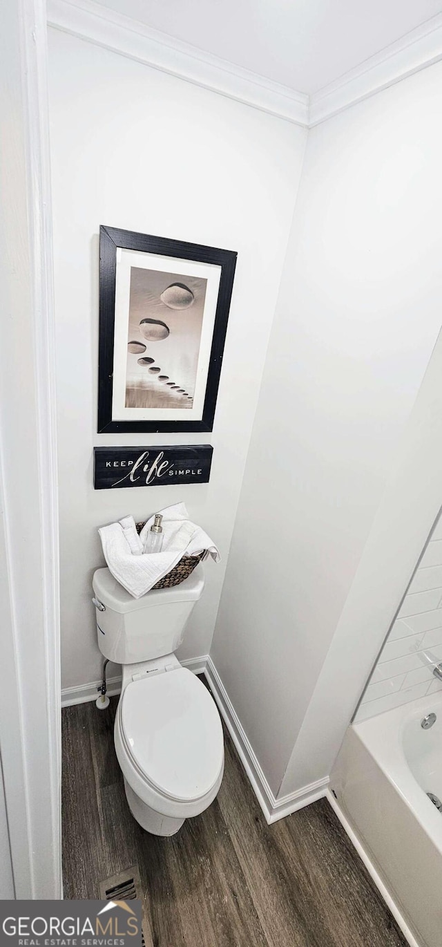 bathroom with baseboards, wood finished floors, toilet, and crown molding