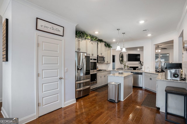 kitchen featuring crown molding, appliances with stainless steel finishes, a center island, dark wood-type flooring, and visible vents