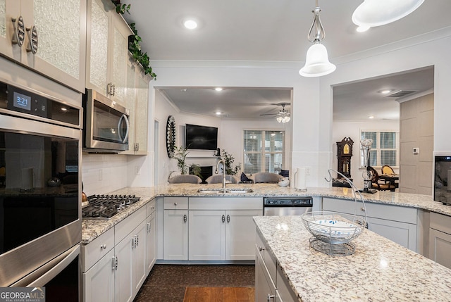 kitchen with ornamental molding, a sink, open floor plan, a ceiling fan, and appliances with stainless steel finishes