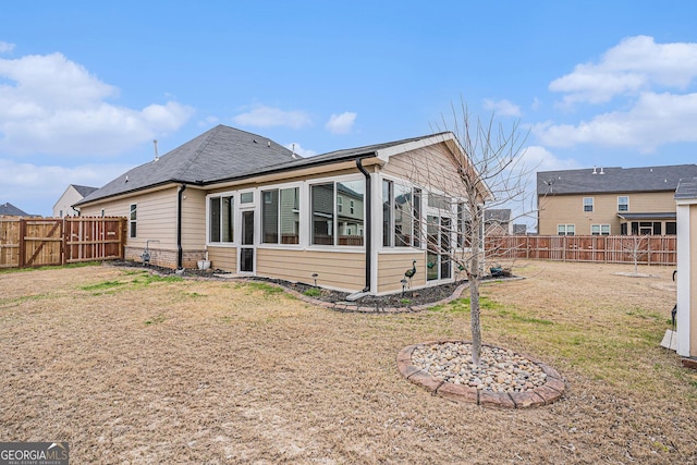 rear view of house with a lawn and a fenced backyard
