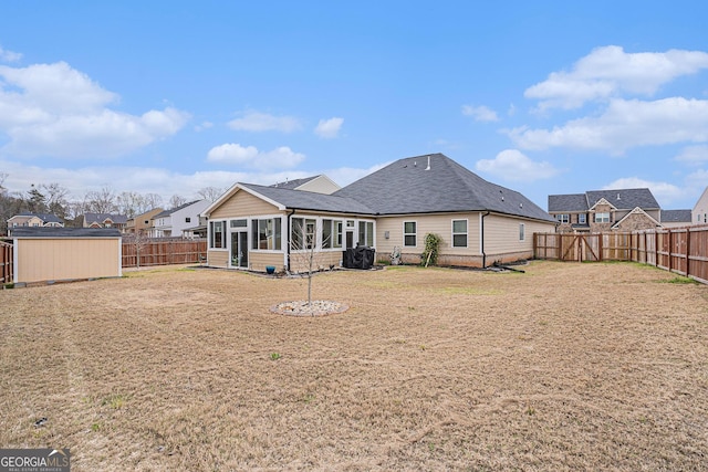 back of property with a sunroom, a fenced backyard, a yard, and an outdoor structure