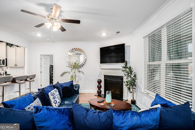 living room featuring ceiling fan, a fireplace, baseboards, wood finished floors, and visible vents
