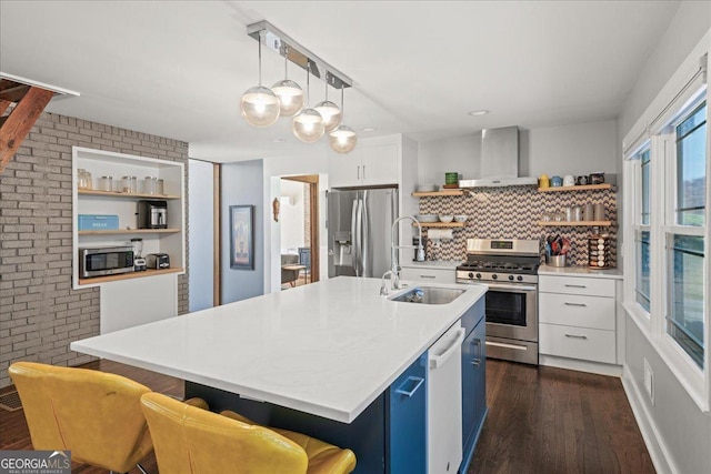 kitchen featuring wall chimney range hood, stainless steel appliances, a sink, open shelves, and blue cabinets