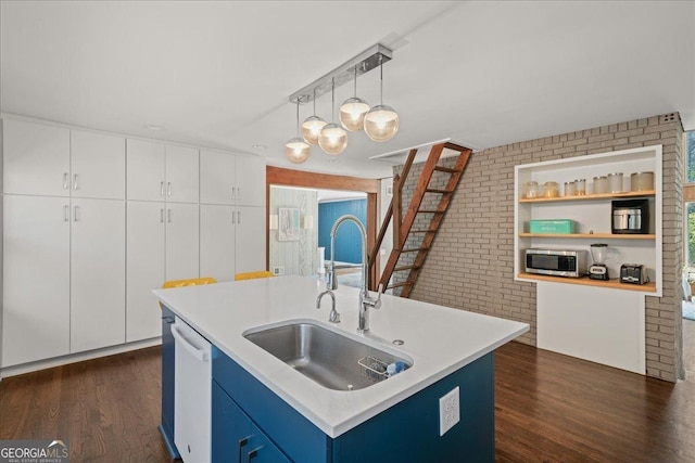 kitchen featuring stainless steel microwave, a sink, dishwasher, blue cabinets, and dark wood-style flooring