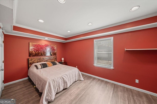 bedroom with wood finished floors, crown molding, baseboards, recessed lighting, and a tray ceiling
