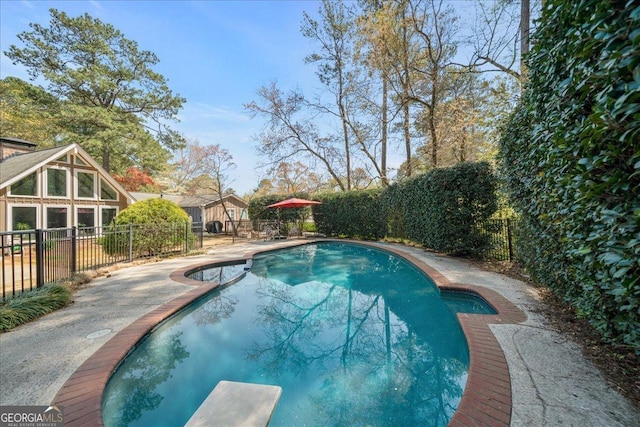 view of pool featuring a diving board, a fenced backyard, and a patio area