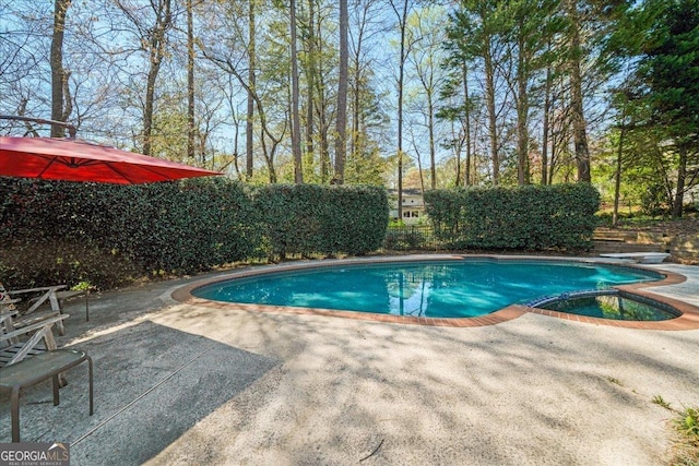 view of swimming pool with a patio area, a pool with connected hot tub, and fence