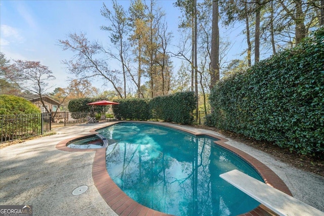 view of swimming pool with a diving board, a fenced backyard, a patio area, and a pool with connected hot tub