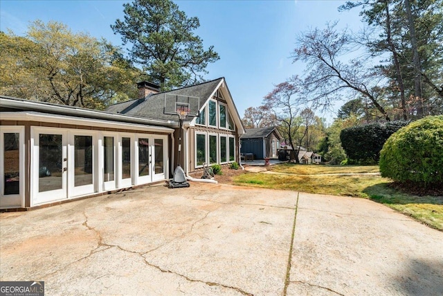 rear view of house with french doors, a patio, a shed, an outbuilding, and a chimney