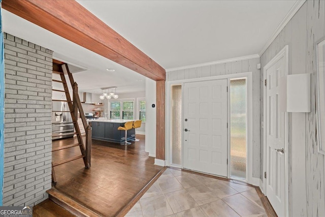 entrance foyer with a chandelier, crown molding, baseboards, and light tile patterned floors