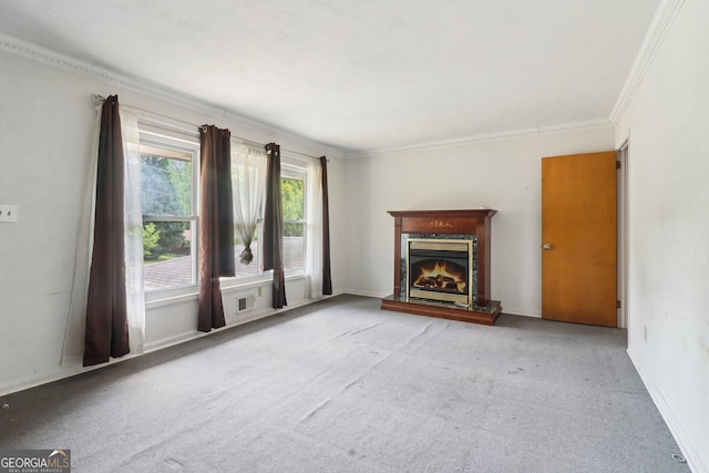 unfurnished living room featuring a lit fireplace, crown molding, visible vents, and carpet