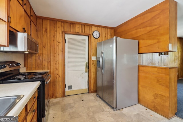 kitchen featuring light countertops, wood walls, brown cabinets, stainless steel appliances, and a sink