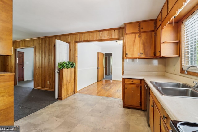 kitchen with wooden walls, light countertops, open shelves, brown cabinetry, and a sink