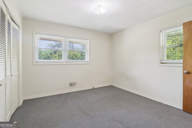 unfurnished bedroom featuring a closet, multiple windows, and carpet flooring