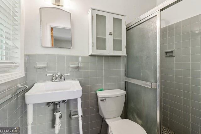 full bathroom with toilet, tile walls, a stall shower, and a sink