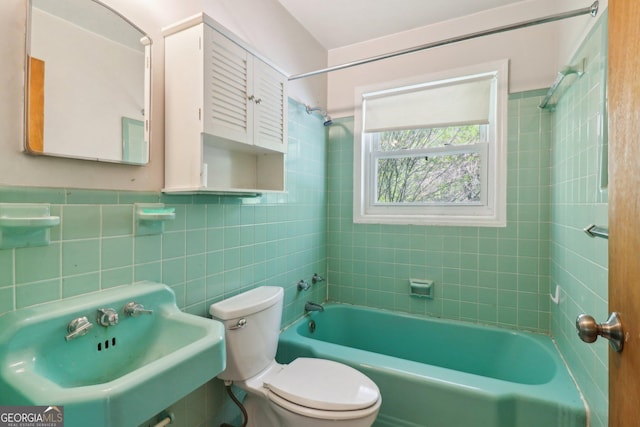 bathroom with toilet, a sink, bathtub / shower combination, and tile walls