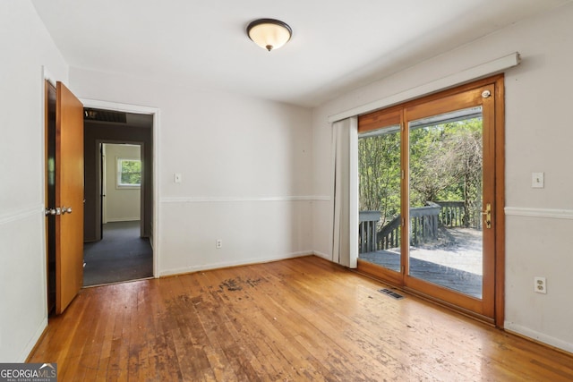empty room with baseboards, plenty of natural light, and hardwood / wood-style flooring