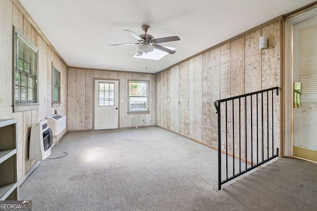 unfurnished room featuring wood walls, carpet, heating unit, and ceiling fan