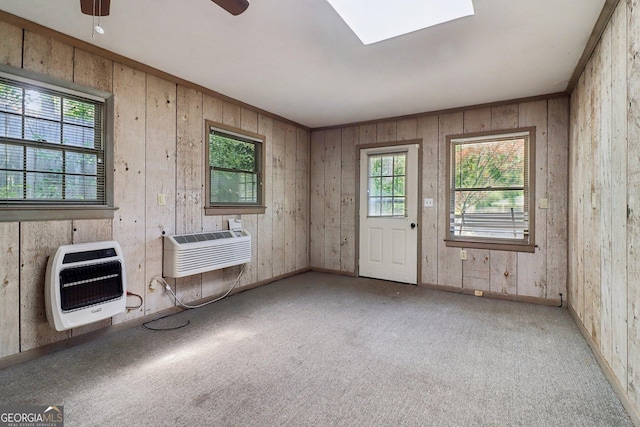 interior space featuring ceiling fan, a skylight, an AC wall unit, wooden walls, and heating unit