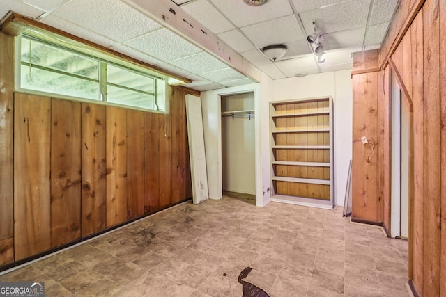 below grade area with wood walls, built in shelves, and rail lighting