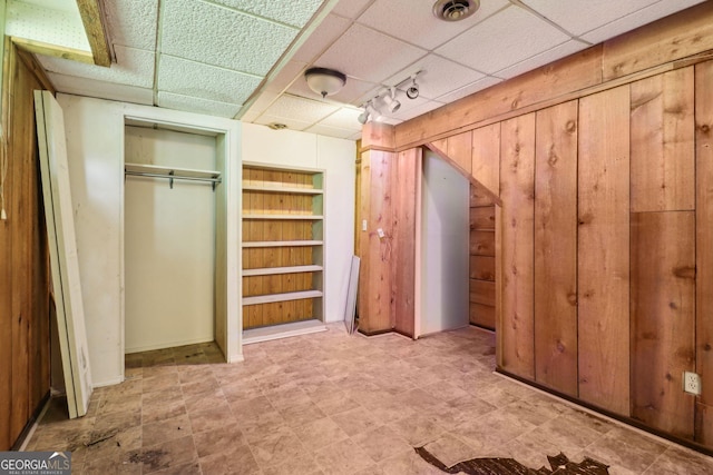 interior space featuring visible vents, a paneled ceiling, and wood walls