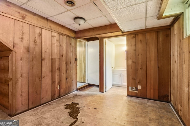 interior space featuring wooden walls, visible vents, and a drop ceiling