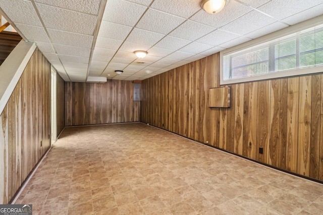 below grade area featuring wood walls and a paneled ceiling