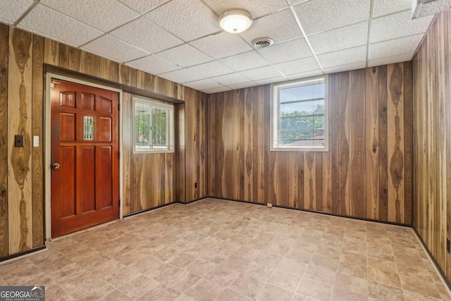 interior space with wooden walls, visible vents, a wealth of natural light, and a paneled ceiling