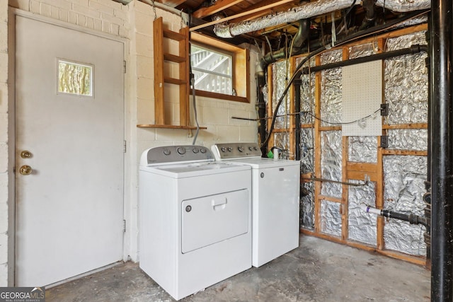 laundry room with concrete block wall, separate washer and dryer, and laundry area