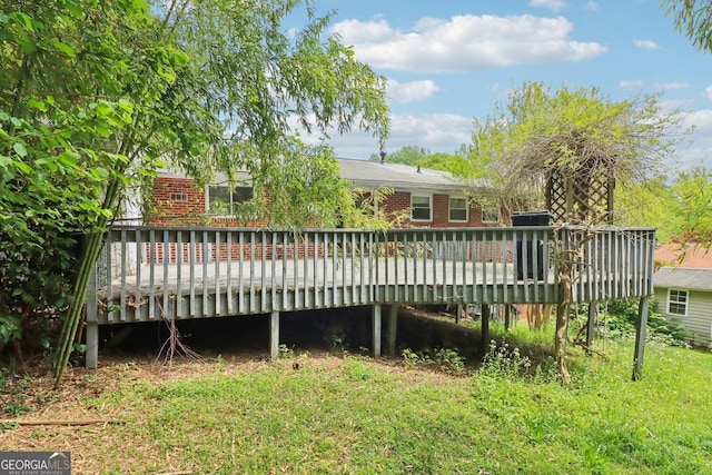 back of house featuring brick siding and a wooden deck