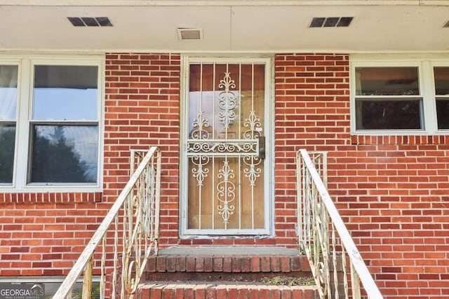 view of exterior entry with visible vents and brick siding