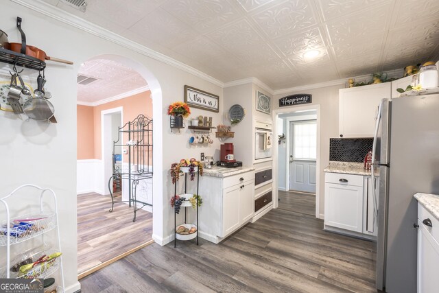 622 Cedartown Ave, Tallapoosa, GA 30176 - kitchen with freestanding refrigerator, arched walkways, dark wood-type flooring, white cabinets, and ornamental molding