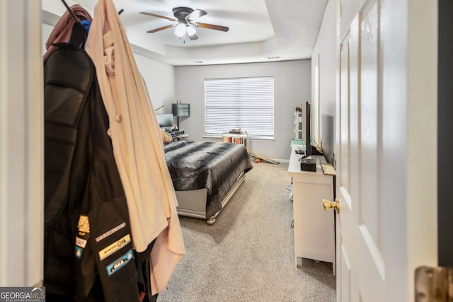 bedroom with carpet, ceiling fan, and a raised ceiling