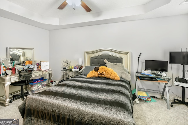 bedroom featuring a tray ceiling, carpet flooring, and a ceiling fan