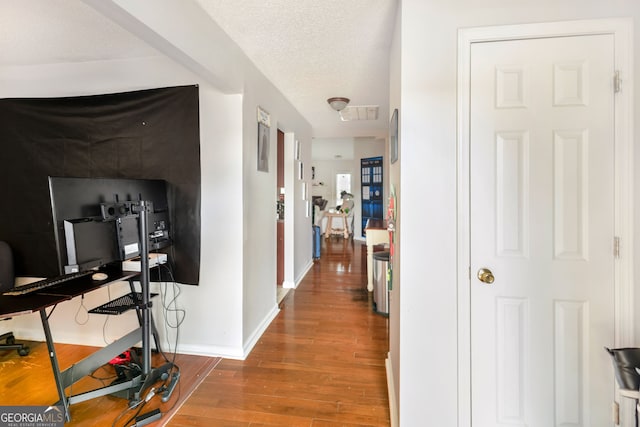 hall with visible vents, baseboards, wood finished floors, and a textured ceiling