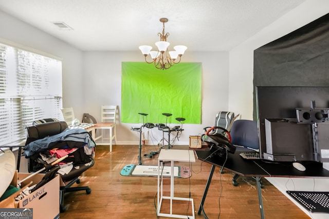 office space with visible vents, baseboards, a notable chandelier, and wood finished floors