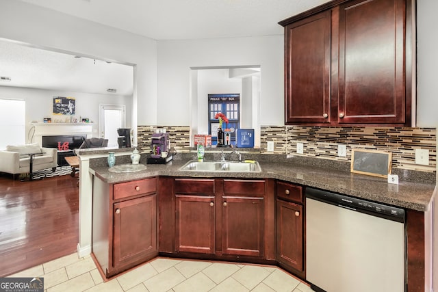 kitchen featuring a sink, dark brown cabinets, dishwashing machine, and a fireplace
