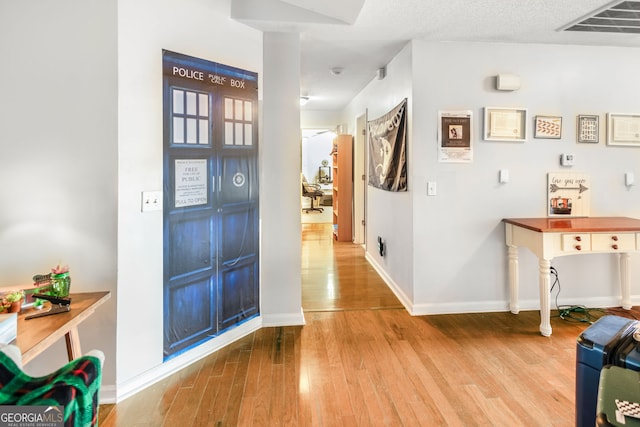 foyer with visible vents, baseboards, wood finished floors, and a textured ceiling