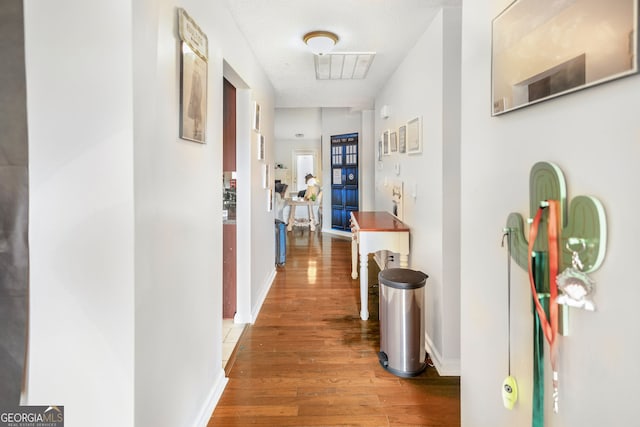 hall featuring wood finished floors, baseboards, and visible vents