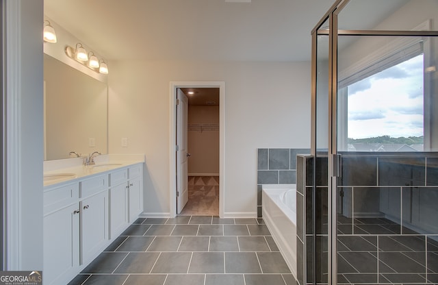 255 Arnewood Cir, Mcdonough, GA 30253 - bathroom featuring double vanity, a garden tub, a spacious closet, tile patterned floors, and baseboards