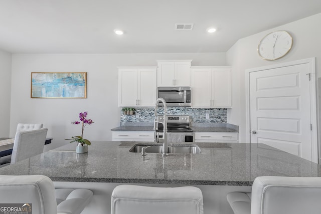 kitchen with visible vents, a sink, appliances with stainless steel finishes, and a kitchen breakfast bar