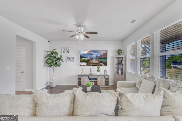 living room featuring baseboards, a ceiling fan, wood finished floors, and visible vents